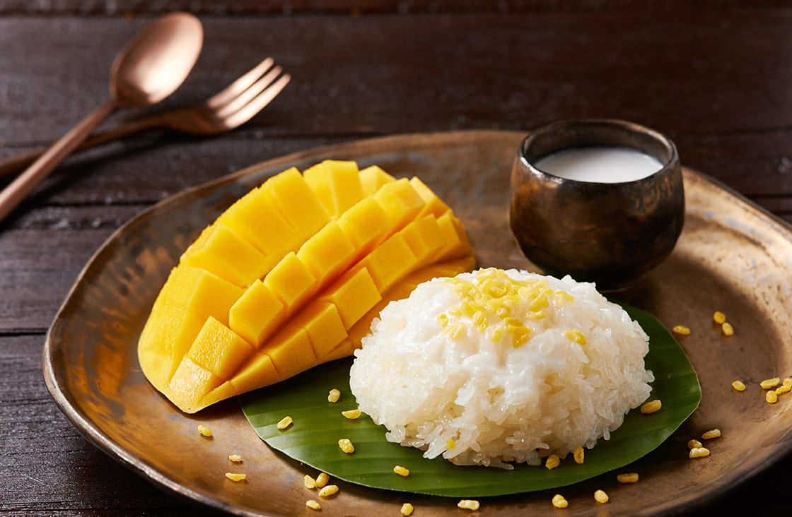 Ahşap bir masa ve bakır çatal ve kaşık üzerinde Mango Yapışkan Pirinç