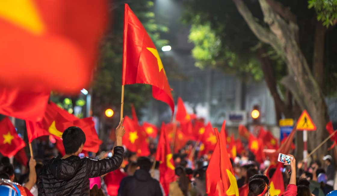 Vietnam bayrakları taşıyan insanlarla dolu sokak