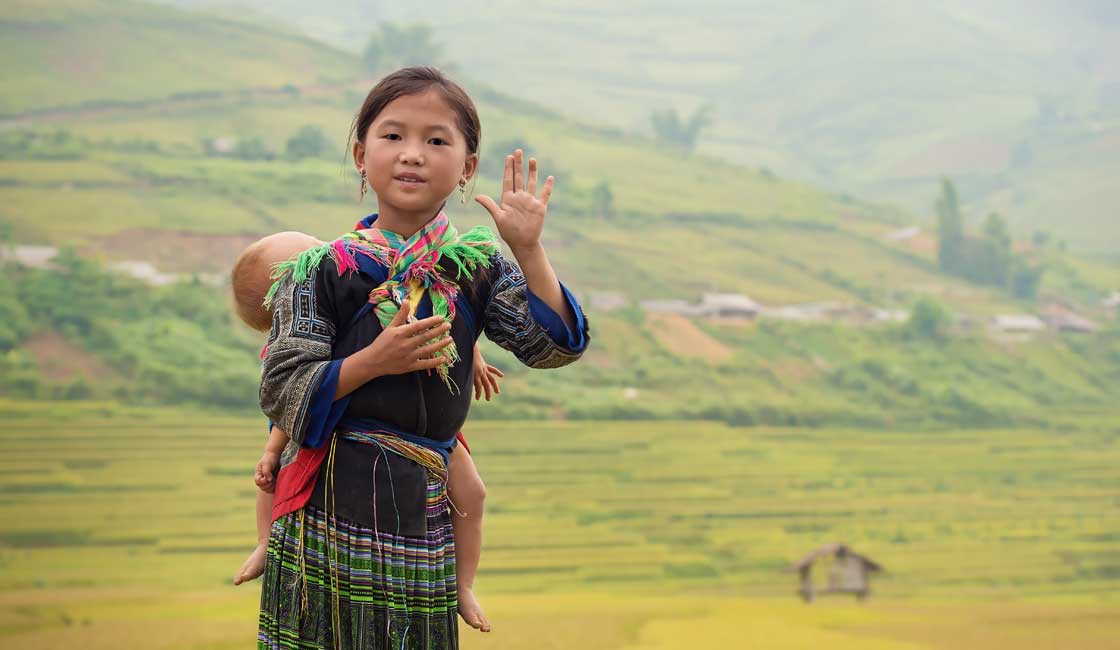 Hmong girl carrying a sleeping toddler