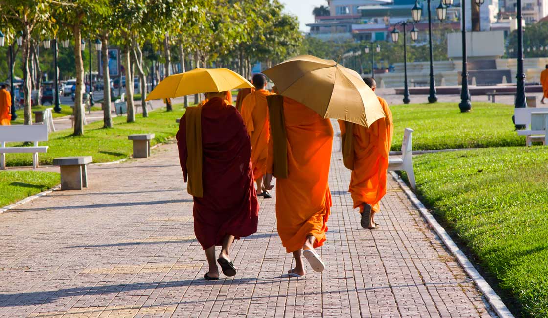 Turuncu şemsiyelerin altında yürüyen rahipler
