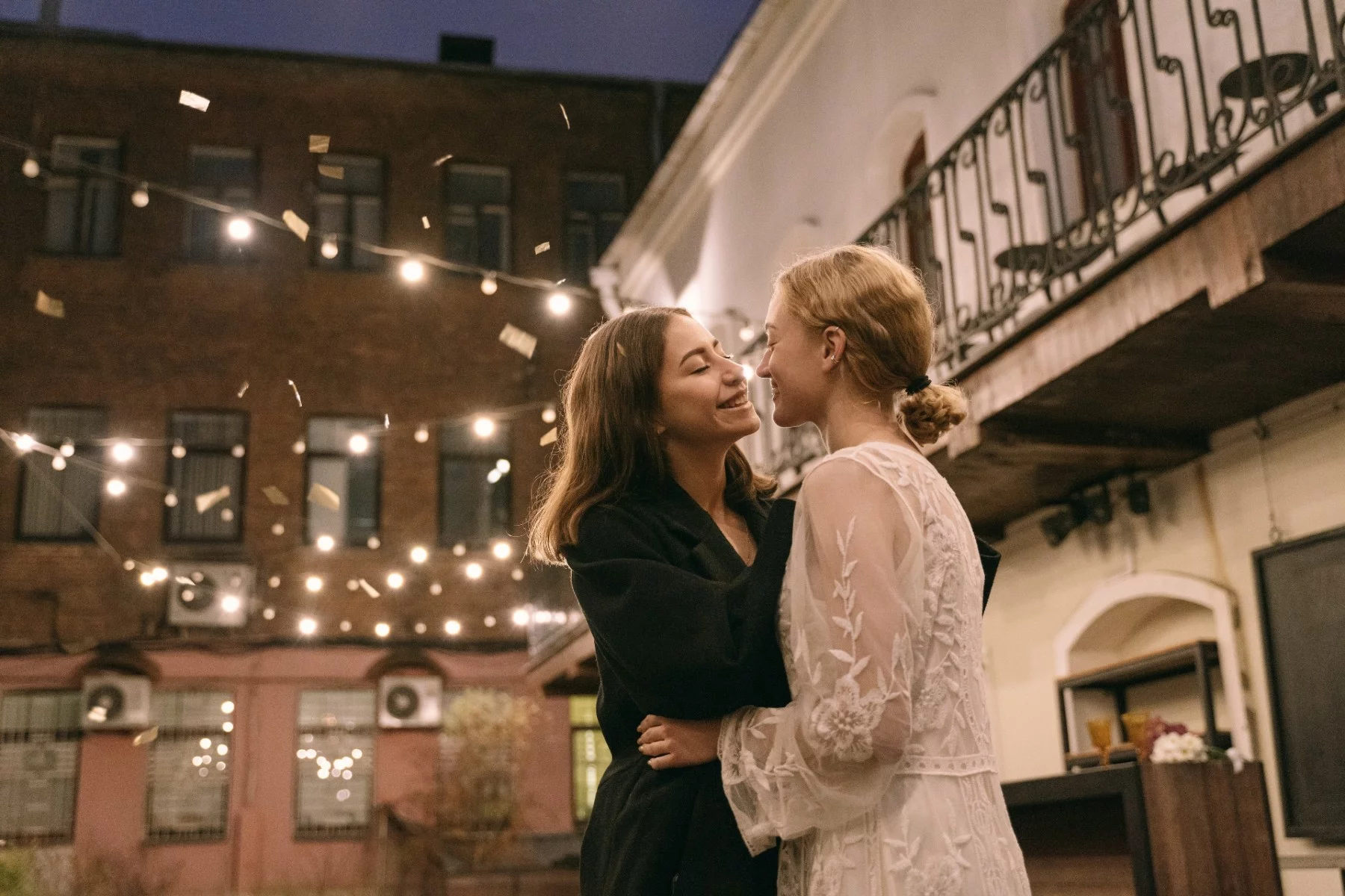 Siyah uzun kollu gömlekli kadın beyaz çiçekli elbiseli kadını öpüyor - düğünlerini kutluyor
