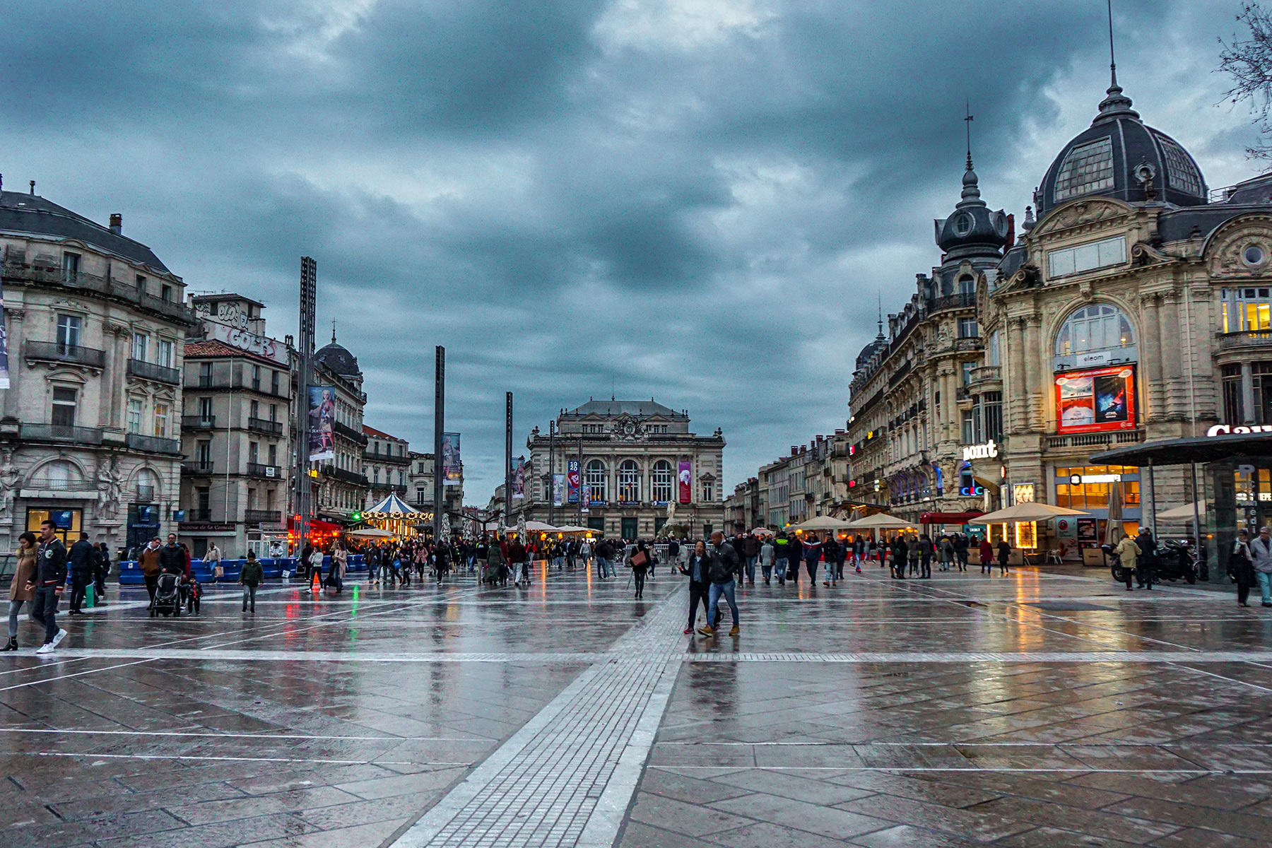 Yağmurlu bir günde Montpellier'de büyük bir meydan. Arka planda lunapark