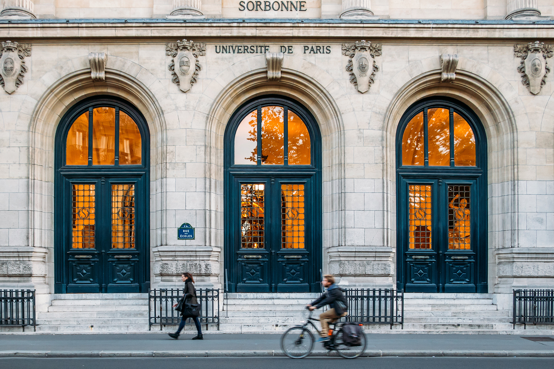Sorbonne Üniversitesi'nin dış görünüşü, yanından geçen ve bisiklete binen insanlar